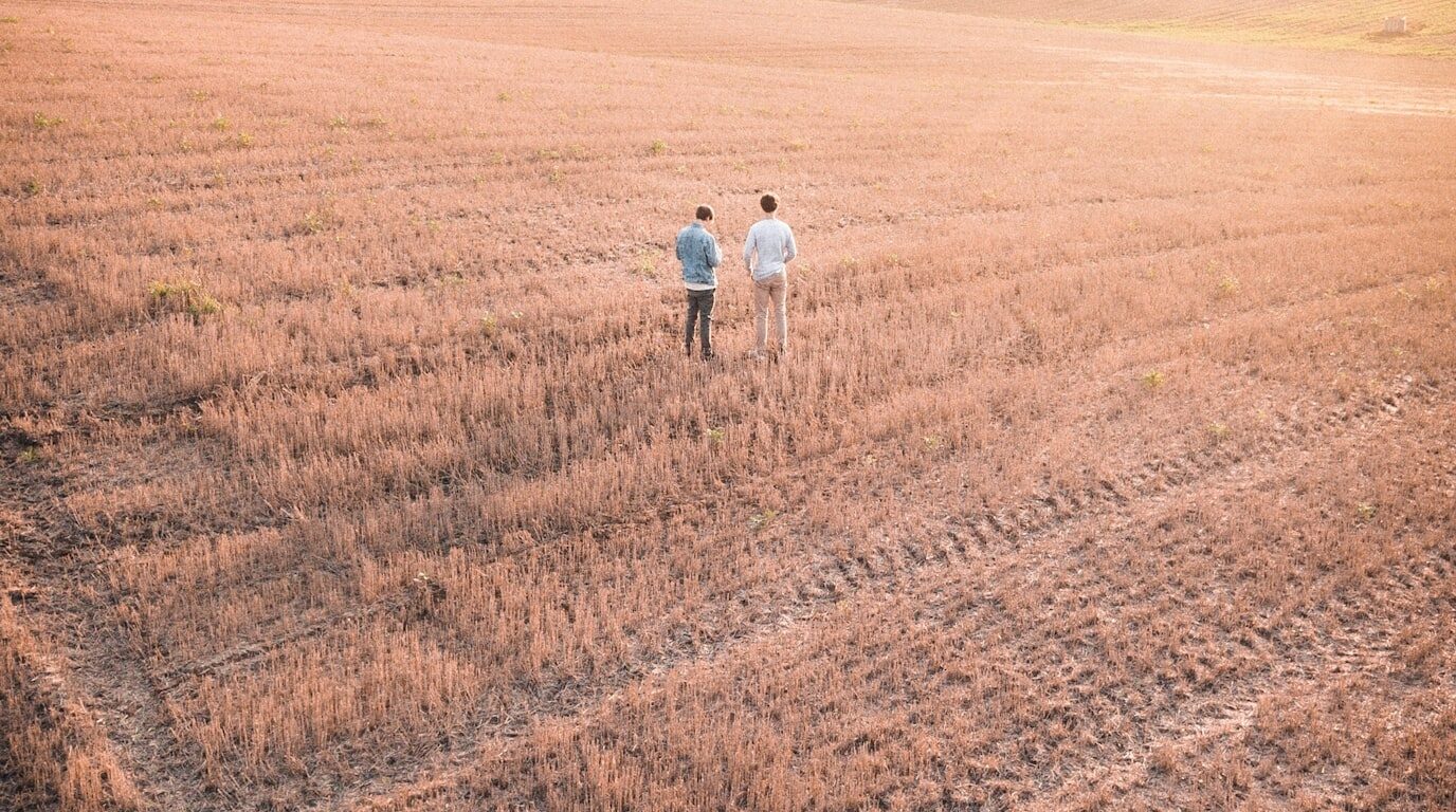 Two people talking together in a farm field.